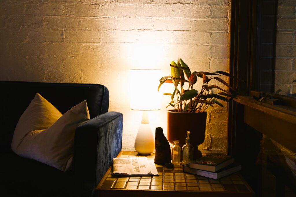 Sydney depicts a navy couch in the living room with a side table, lamp and decorative objects