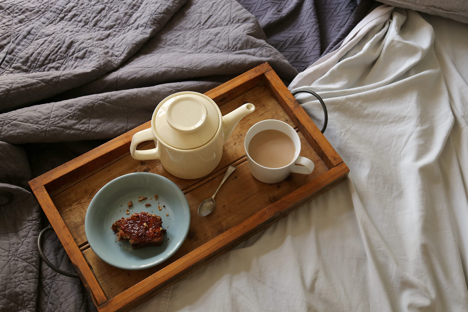 Sydney features a breakfast tray on a bed with teapot, mug of tea and a pastry snack on cream and navy sheets